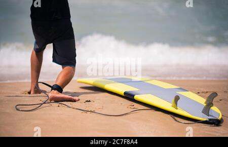 Istruttore di surf mostra sulla spiaggia soleggiata come stare in piedi sul surf. Lezioni di surf Foto Stock