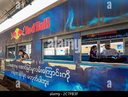 Una giovane donna birmana si affaccia da una finestra su una carrozza ferroviaria sulla ferrovia circolare Yangon a Yangon, Myanmar Foto Stock