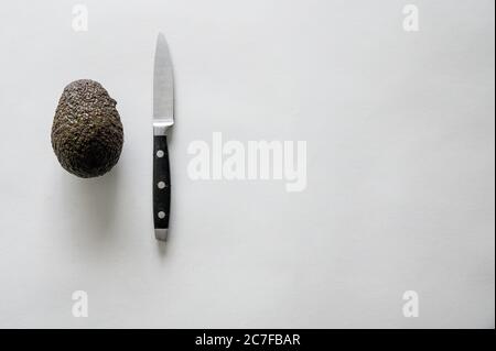 Un ottimo angolo di un delizioso avocado fresco con un coltello su una superficie bianca Foto Stock