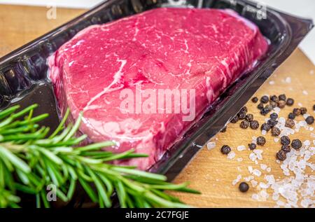 Bistecca di manzo e spezie confezionate sotto vuoto su tagliere di legno Foto Stock