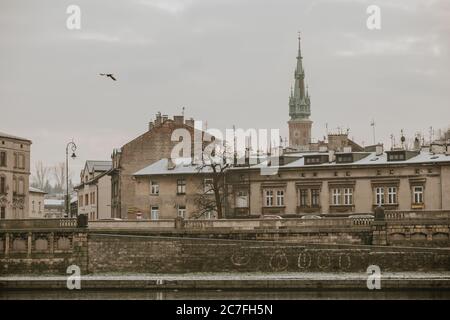 Edifici sul lungomare del fiume Vistola nella città polacca di Cracovia con la torre della chiesa cattolica Église San Giuseppe sullo sfondo Foto Stock