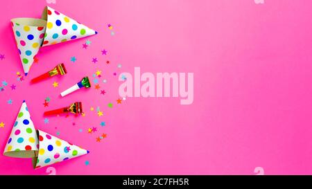 Cappelli e accessori per la festa di compleanno giacciono su sfondo rosa brillante. Confetti sparsi. Spazio di copia per il testo. Vista dall'alto. Disposizione piatta. Lay Foto Stock