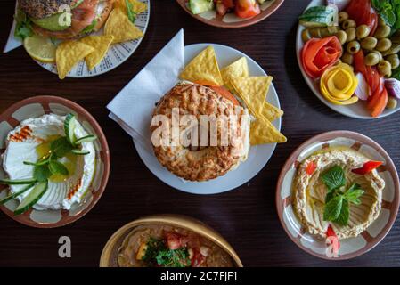 Foto ad alto angolo di una bagel e scaglie di tortilla circondato da altri piatti deliziosi Foto Stock