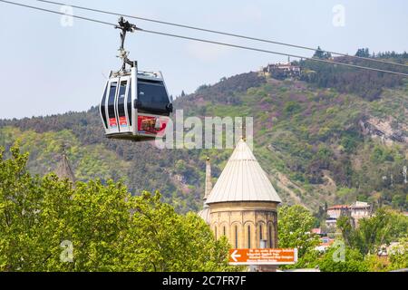 Tbilisi, Georgia - 29 aprile 2017: Cabina rossa della funivia di Tbilisi e torre della chiesa Foto Stock