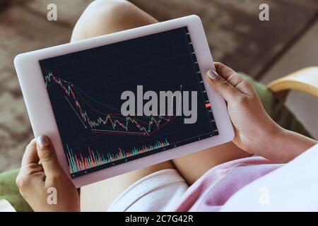 Analisi. Donna che lavora a casa durante la quarantena del coronavirus o COVID-19, concetto di ufficio remoto. Giovane capo, manager di fronte al tablet durante l'analisi di grafici, statistiche. Avvicinati con il dispositivo. Foto Stock