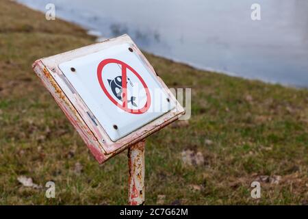 Qui non è consentito pescare, cartello di attenzione sulla costa del lago, foto ravvicinata con messa a fuoco selettiva Foto Stock