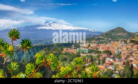 Vista panoramica aerea del vulcano Etna e della città di Taormina. Tetti di molte abitazioni. Fumo sul vulcano Etna innevato. Taormina, Sicilia, Italia. Foto Stock