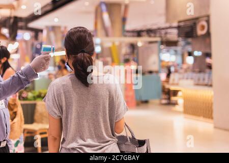 Guardia di sicurezza che controlla la temperatura della donna all'ingresso del centro commerciale. Foto Stock