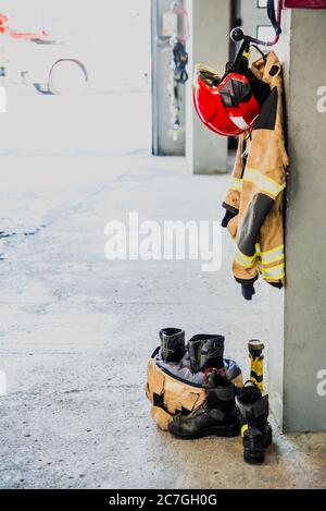 Stivali e giacca da fuoco sul pavimento del garage di una stazione antincendio. Foto Stock