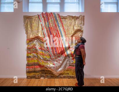 Londra, Regno Unito. 17 luglio 2020. Focus sulla mostra El Anatsui a ottobre la Galleria si svolge dal 15 luglio all'8 agosto 2020, mostrando opere in metallo e una selezione di stampe create in collaborazione con il factum Arte, Madrid. El Anatsui è oggi più conosciuto per le sue opere composte da molte migliaia di bottiglie in alluminio. Gallery Manager Saara studia le modifiche all'installazione in Fortune, 2018, alluminio e rame. Credit: Malcolm Park/Alamy Live News. Foto Stock