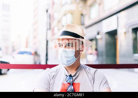 Un uomo con un cappello sulla strada indossa una maschera Foto Stock