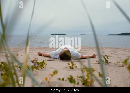 Giovane uomo che fa yoga su un lago in una giornata estiva, meditazione, relax posa Foto Stock