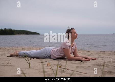 Donna che fa il Cobra Yoga stretch su tappetino yoga Foto Stock