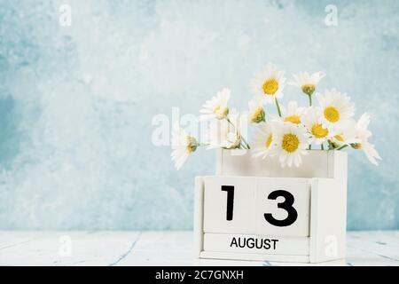 Calendario cubo bianco per agosto decorato con fiori margherita su blu con spazio copia Foto Stock