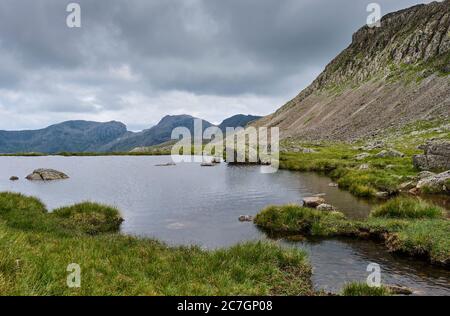 SCA cadde, Scafell Pike e Bowfell visti da tre Tarns vicino Crinkle Crags, vicino a Langdale, Lake District, Cumbria Foto Stock