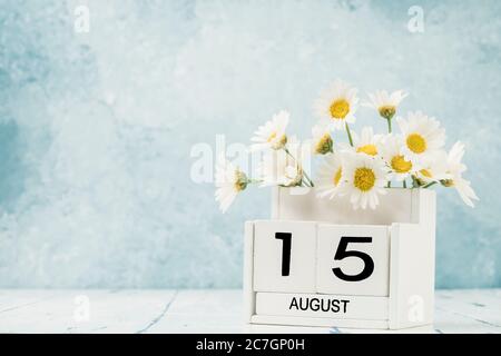 Calendario cubo bianco per agosto decorato con fiori margherita su blu con spazio copia Foto Stock