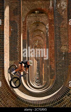 Joe Bowers guida la sua BMX bike mentre la gente goda una giornata fuori al Viadotto della Valle di Ouse a Balcombe, Sussex occidentale. Foto Stock