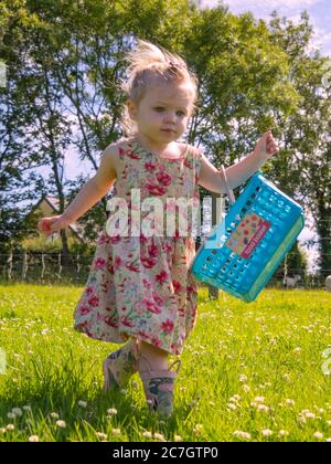 Toddler con un cestino che gioca in giardino, Regno Unito Foto Stock