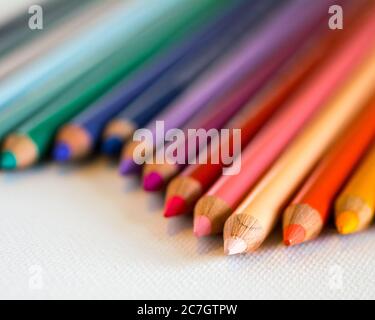 Closeup di matite colorate su un tavolo bianco sotto luci con sfondo sfocato Foto Stock