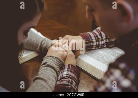 Giovane coppia stringendo le mani mentre si siede a un tavolo leggere libri Foto Stock