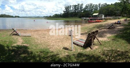 Spiaggia Playa Laguna circondata dal lago e dal verde sotto Un cielo nuvoloso in Argentina Foto Stock