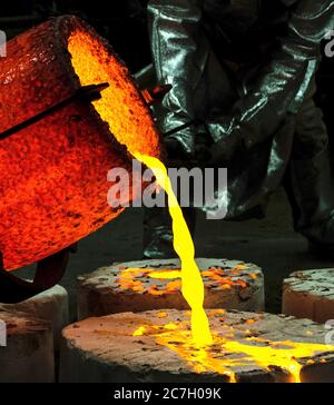 lavoratore in una suite di protezione bruciare metallo liquido fusione in una fonderia fabbrica Foto Stock