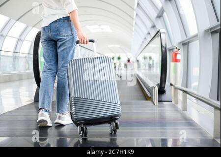 Vacanza e concetto estivo, una donna con valigia a piedi nel terminal dell'aeroporto Foto Stock