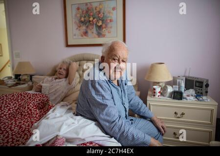 Una coppia anziana negli anni 80 si sedette sul letto nei pigiami prima di alzarsi al mattino, in Inghilterra, Regno Unito Foto Stock