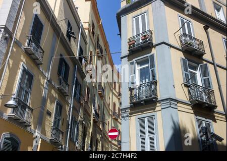 Vista delle facciate con case colorate con finestre e balconi in una strada a Cagliari, Italia con un cartello di traffico veicolare senza ingresso Foto Stock