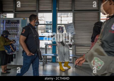 Giacarta, Giacarta, Indonesia. 17 luglio 2020. Un dipendente che indossa un equipaggiamento protettivo come precauzione contro il nuovo coronavirus ha un banner che mostra informazioni sul virus e su quelli infetti presso la stazione centrale di Harmoni a Giacarta, Indonesia, il 17 luglio 2020. Secondo il funzionario del ministero della sanità, i casi COVID-19 in Indonesia sono saliti di 1,462 in un giorno a 83,130, con il numero di morti che si è aggiunto di 84 a 3,957. Nelle ultime 24 ore, nove province hanno registrato un numero elevato di casi. Credit: Afriadi Hikmal/ZUMA Wire/Alamy Live News Foto Stock