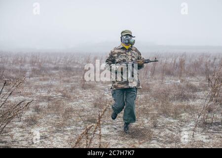 soldato che corre in battaglia con maschera a gas Foto Stock