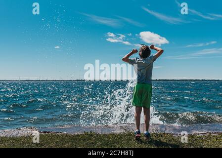 Ragazzo che si è tuffato sulla riva di un lago in una giornata estiva soleggiata. Foto Stock