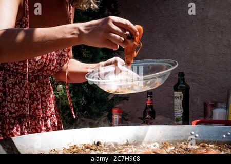 donna che prepara una fideuá spagnola con gamberi e tagliatelle in paella Foto Stock