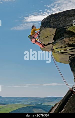 Donna che arrampica sulle rocce di Windgather nel British Peak District Foto Stock