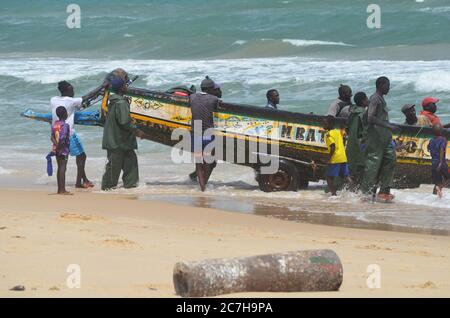 Pescatori artigianali che spingono le piroghe fuori dall'acqua a Lompoul, Senegal Foto Stock