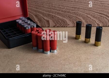 Fuoco selettivo di rosso e nero shotgun shell vicino una scatola di munizioni su una superficie marrone Foto Stock