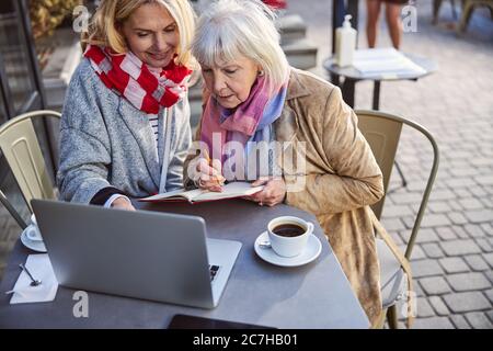 Due belle donne sedute al tavolo con il computer portatile all'aperto Foto Stock