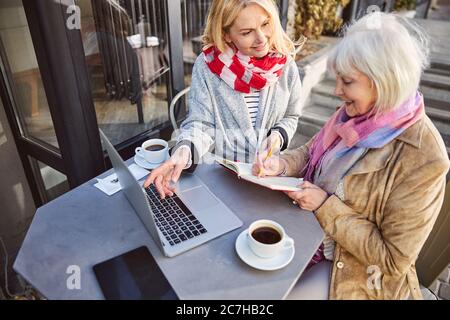 Elegante due Signore seduti nella caffetteria con terrazza e computer Foto Stock