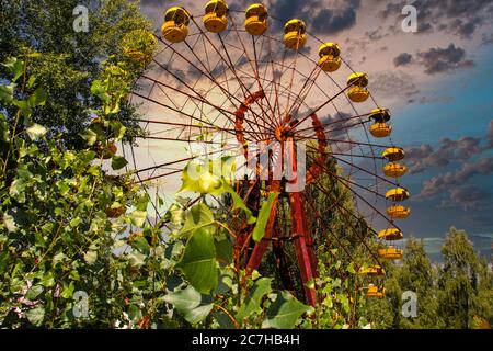 L'iconica ruota panoramica di pripyat nella zona di esclusione su un tramonto rosso dorato in estate. Cielo rosso quasi ardente che indica foreste recenti e incendi Foto Stock