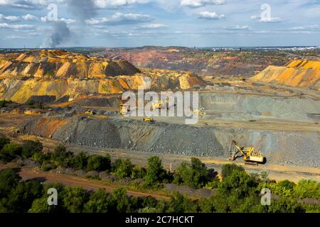 Escavatori e dumper da miniera pesanti in una cava di calcare, caricamento di pietre o vista panoramica aerea industriale. Foto Stock