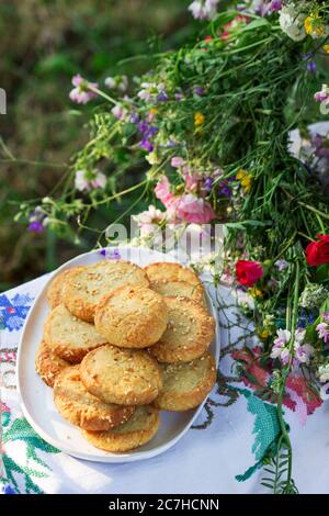 Biscotti shortbread con formaggio blu e semi di sesamo e una corona di fiori selvatici su un'altalena. Stile rustico.