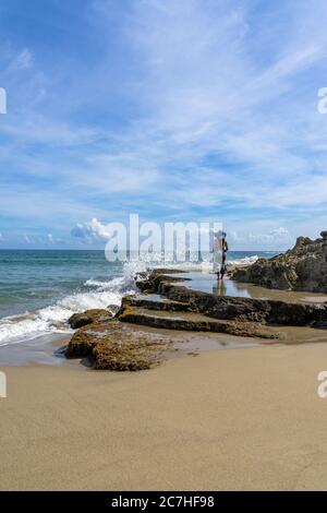 America, Caraibi, grandi Antille, Repubblica Dominicana, Cabarete, donna si erge su una roccia e si affaccia sul mare Foto Stock