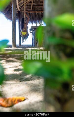 America, Caraibi, Greater Antilles, Repubblica Dominicana, Cabarete, donna seduta su un'oscillazione al bar sulla spiaggia del natura Cabana Boutique Hotel & Spa Foto Stock
