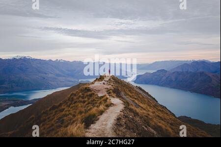 Vista panoramica del Roys Peak in Nuova Zelanda con basse montagne in lontananza sotto il paesaggio nuvoloso Foto Stock