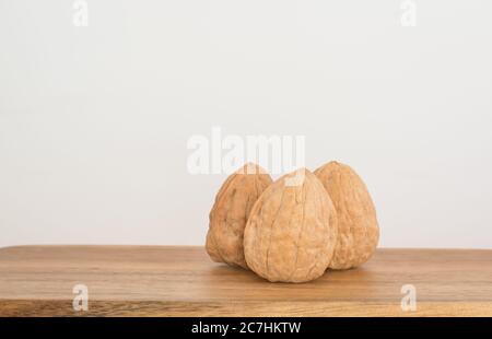 Tre noci intere su una tavola di legno Foto Stock