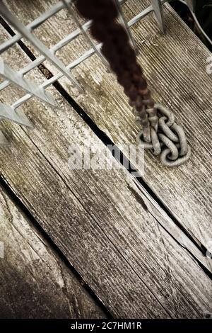 Lunghezza della catena metallica arrugginita su vecchie tavole di legno. Foto Stock