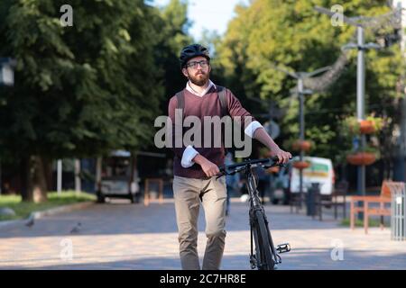 Ritratto di un pendolarista maschile che indossa un casco da bicicletta in una città. Ciclismo sicuro in città, spostamenti in bicicletta, immagine di stile di vita urbano attivo Foto Stock