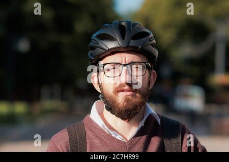 Ritratto di un pendolarista millenario in un casco da bicicletta. Ciclismo sicuro in città, andando a lavorare su una bicicletta, moderna immagine di stile di vita urbano Foto Stock