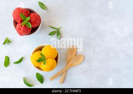 Scoop di gelato in ciotole con fragole e sapori di mango. Vista dall'alto Foto Stock