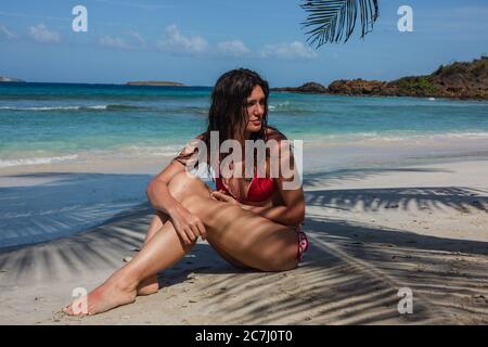 Una donna seduta nella sabbia di Zoni Beach all'ombra di una palma a Culebra, Puerto Rico